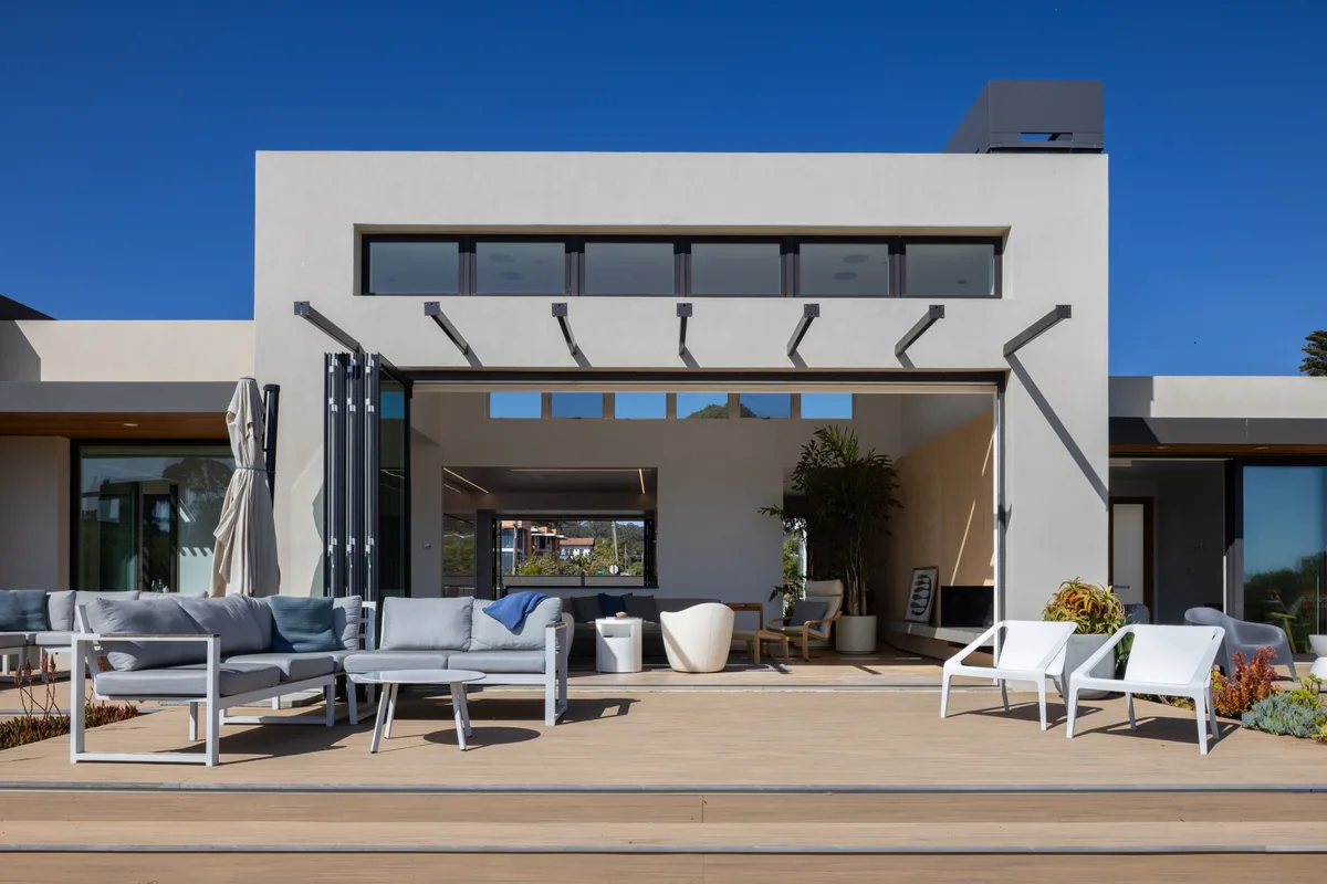 Residence with exterior folding doors opened to a patio