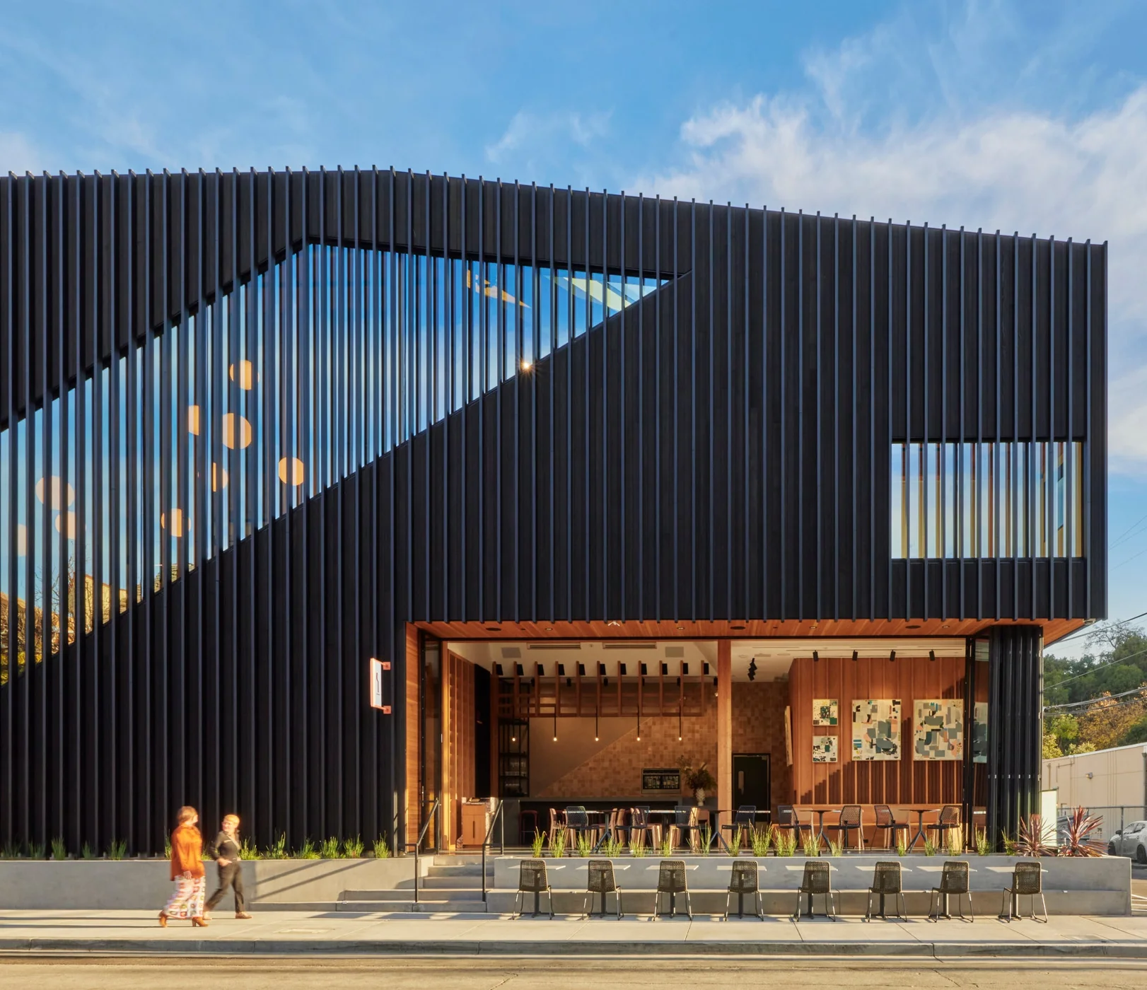 Folding glass wall opening a dark-clad building